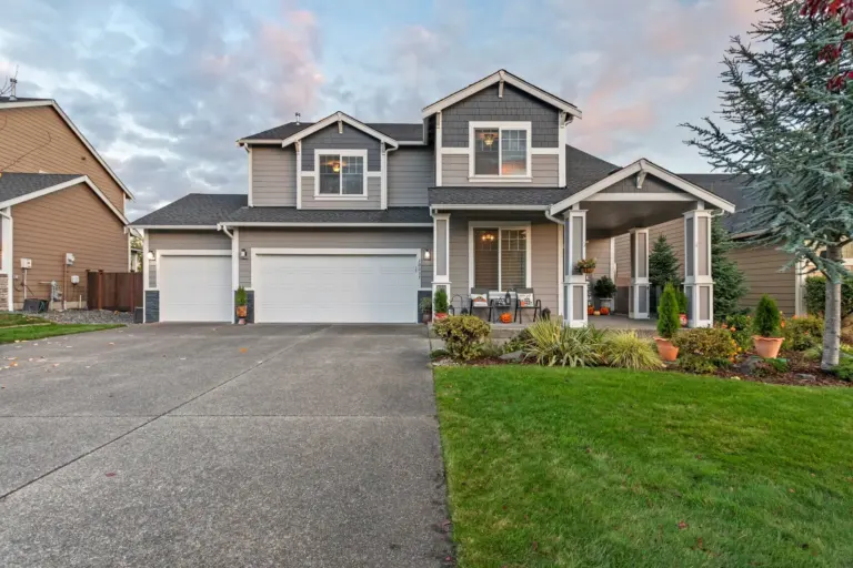 Two-story house with a manicured front lawn and attached garage at dusk in a Washington suburb